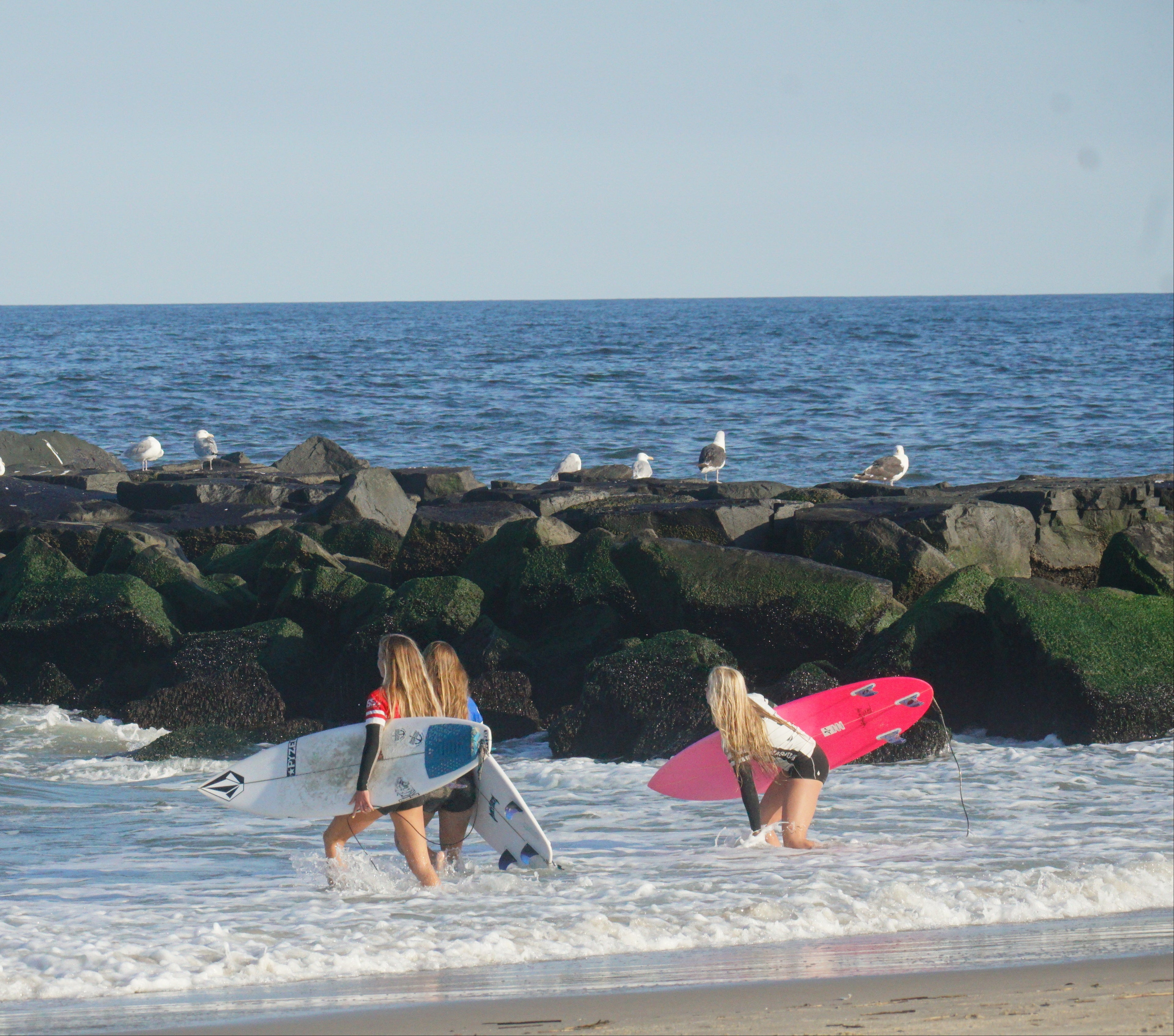 Manasquan High School Girls Team members entering the ocean at Spring Lake Beach, New Jersey.  learn about Manasquan High School Surf Contest results and contest schedule here.