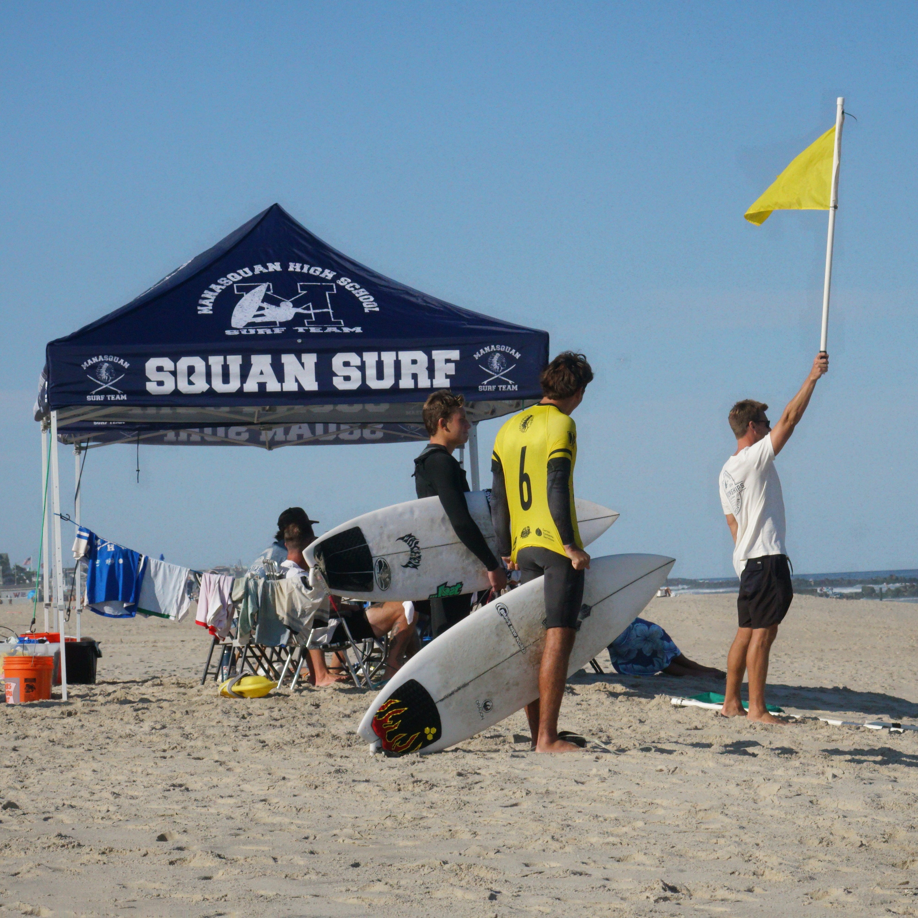 Manasquan surf team Coach Hoffman signaling the next heat is about to begin while  MHS Surfers get ready.